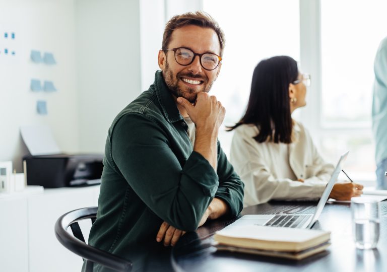 Business,Man,Smiling,At,The,Camera,While,Sitting,In,A