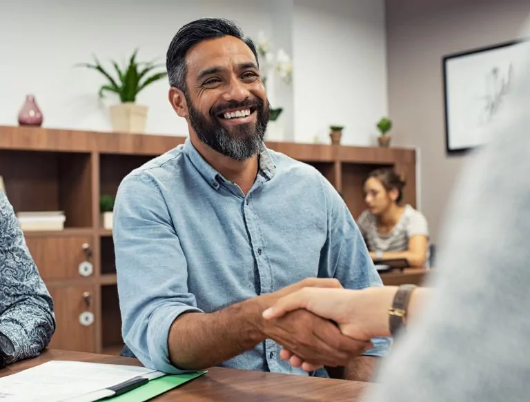 Two,Business,People,Shaking,Hands,While,Sitting,In,Meeting,Room.